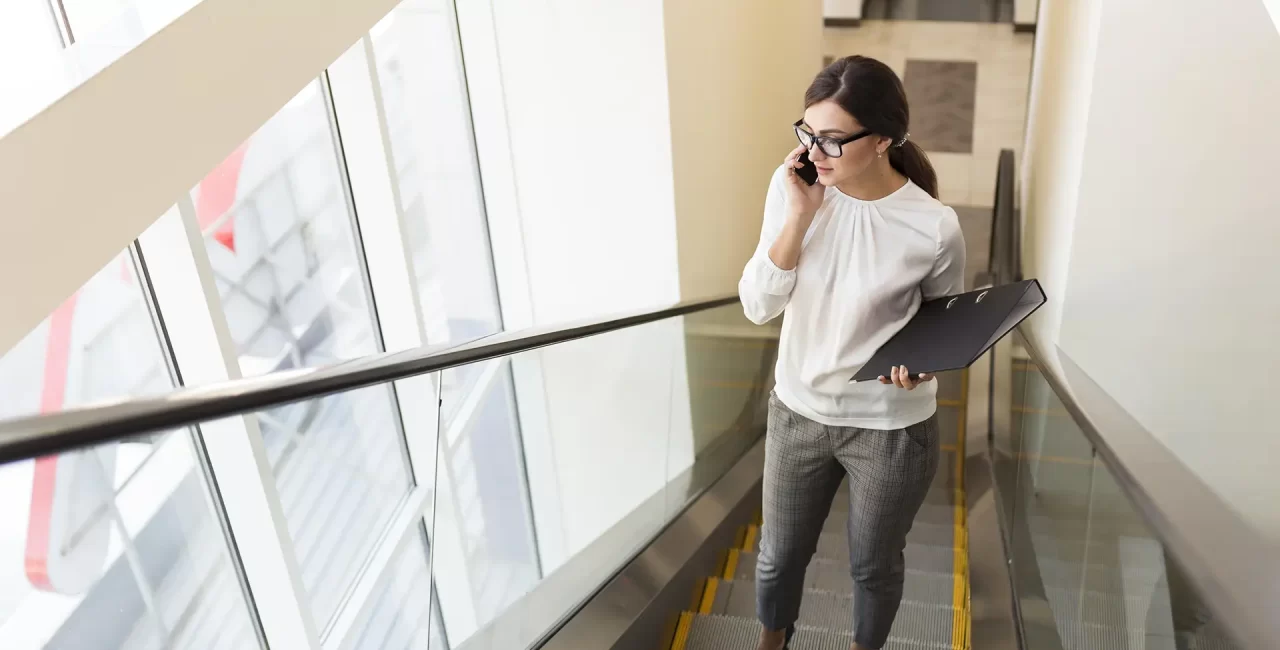 angle-eleve-femme-affaires-classeur-parlant-au-telephone-alors-que-escalator copy